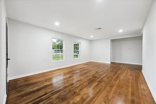 a view of empty room with wooden floor and fan