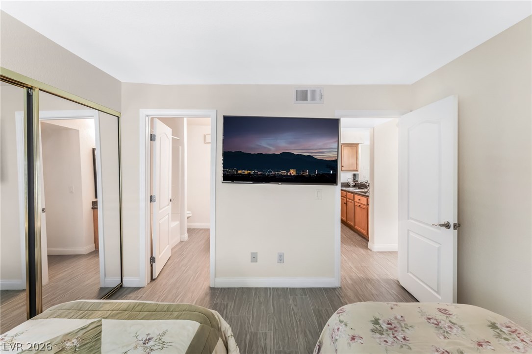 3145 East Flamingo Road, Unit 1092 Las Vegas, NV 89121 - Photo 20 of 33 Hardwood-look flooring extends through this sleeping area, offering easy access to an adjacent bathroom and a kitchen.