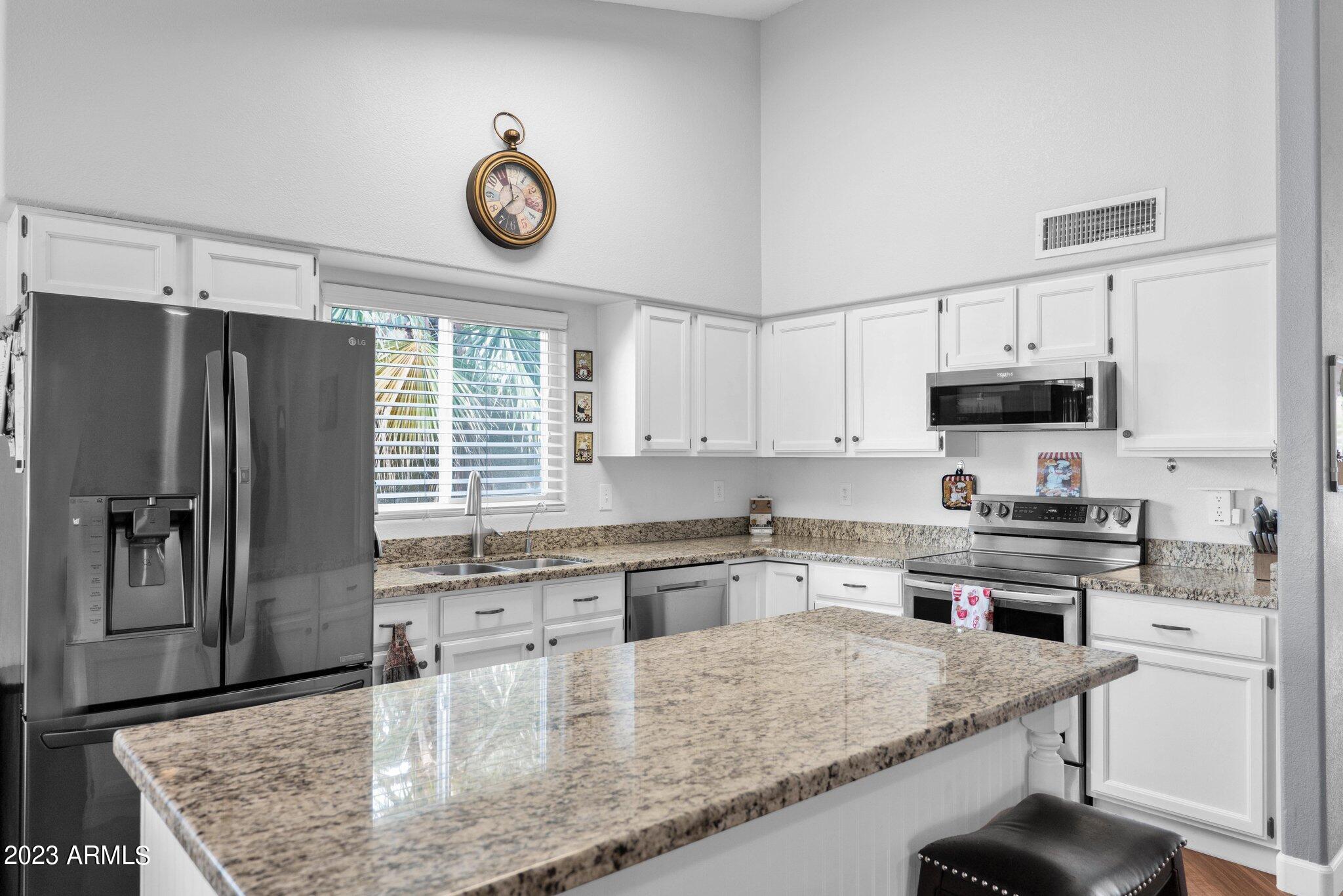 a kitchen with stainless steel appliances granite countertop a sink a stove and a refrigerator
