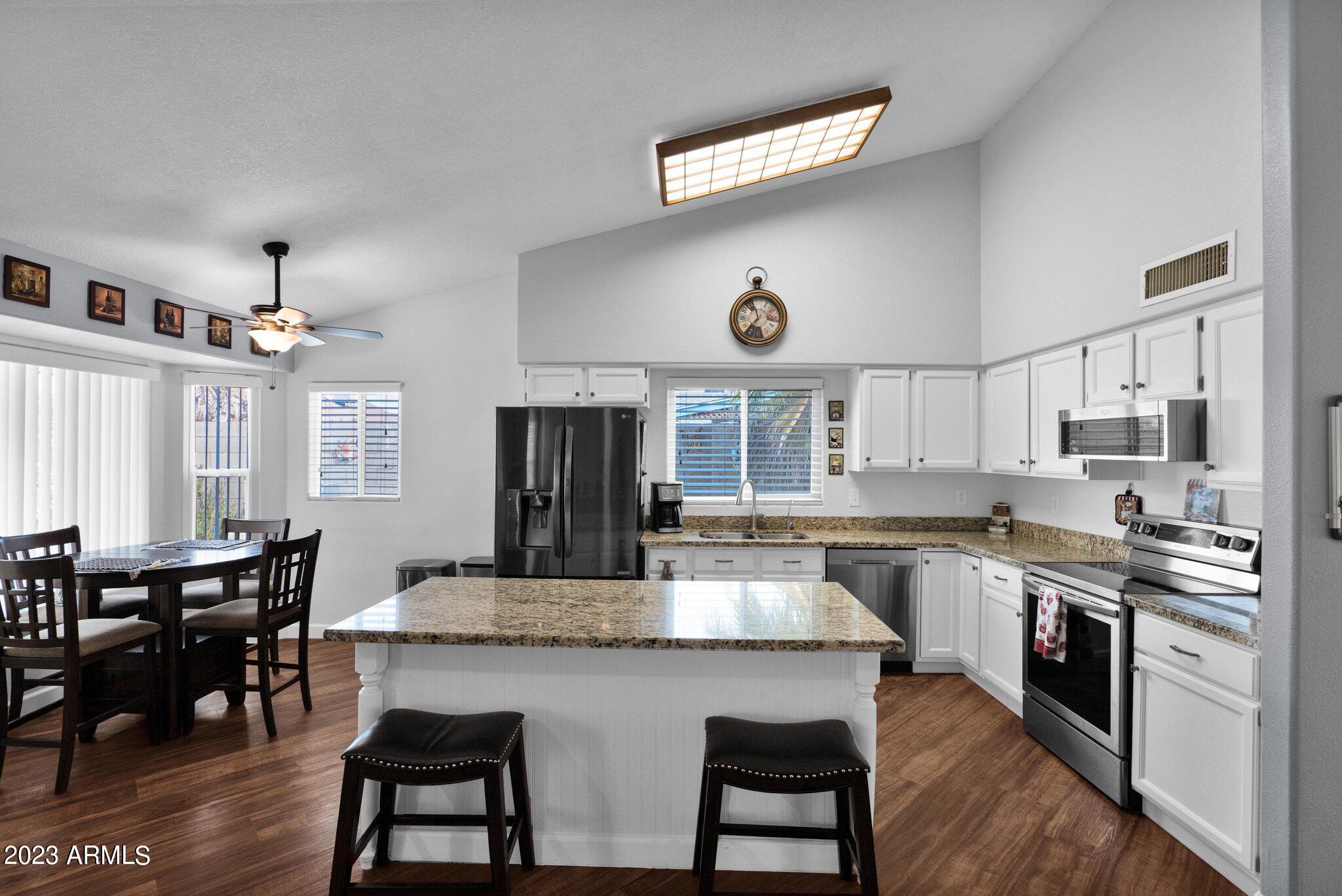 4338 East Douglas Avenue Gilbert, AZ 85234 - Photo 14 of 48 a kitchen with stainless steel appliances granite countertop a stove top oven a sink a dining table and chairs