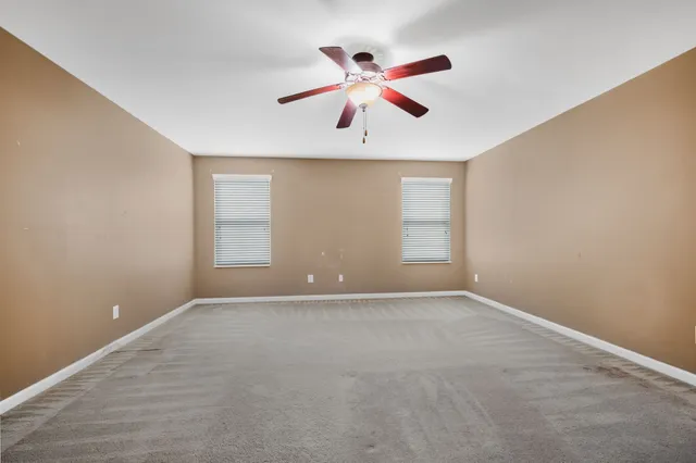 an empty room with ceiling fan and window
