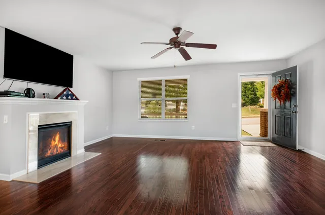 a view of an empty room with wooden floor fireplace and a window