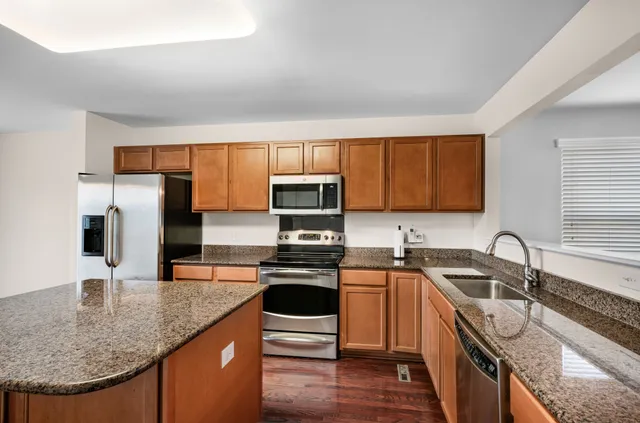 a kitchen with stainless steel appliances granite countertop a sink stove microwave and refrigerator