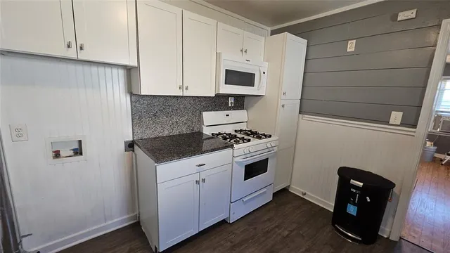 a kitchen with granite countertop white cabinets and white appliances