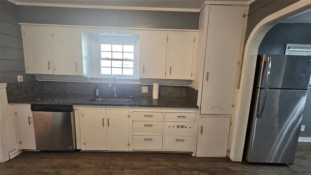 a kitchen with granite countertop white cabinets and refrigerator