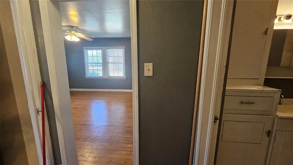 a view of hallway with window and wooden floor