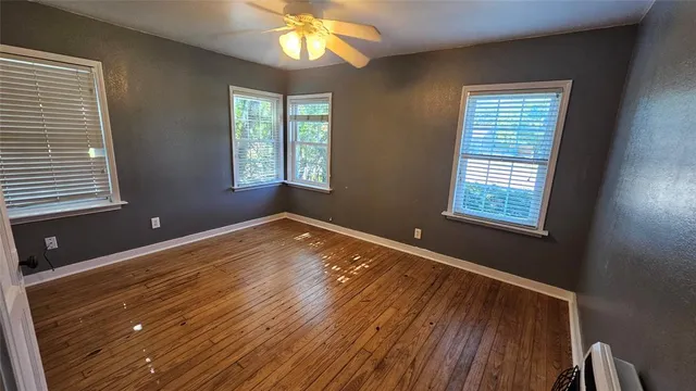 a view of an empty room with a window and wooden floor