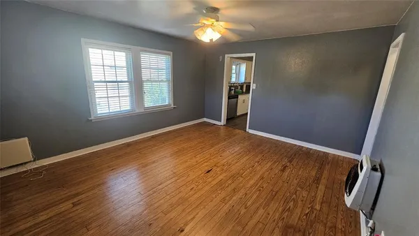 a view of an empty room with window and wooden floor