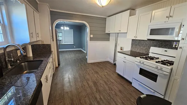 a kitchen with granite countertop a stove a sink and a refrigerator