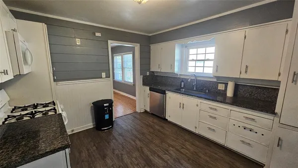 a kitchen with granite countertop white cabinets and black appliances