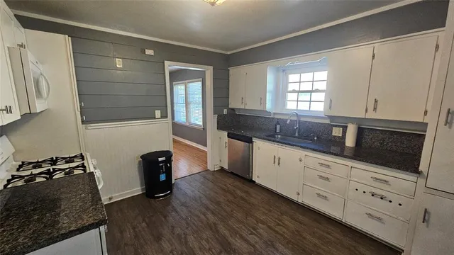 a kitchen with granite countertop white cabinets and black appliances