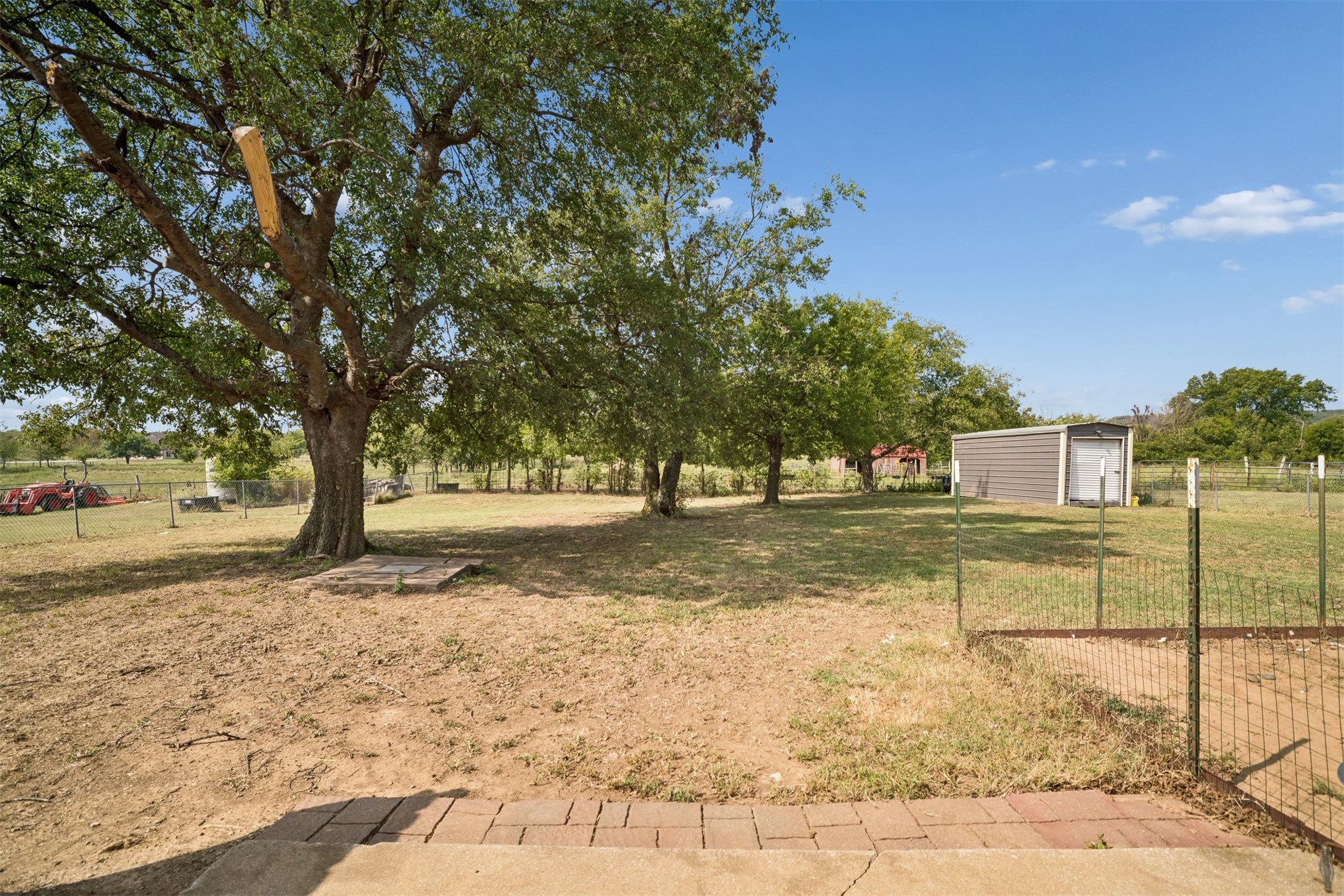 175 Alt 75 Mounds, OK 74047 - Photo 36 of 41 Expansive outdoor area featuring mature trees, a metal storage shed, and perimeter fencing