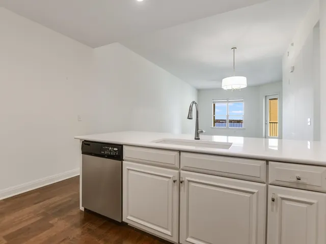 a sink with white cabinets and wooden floor