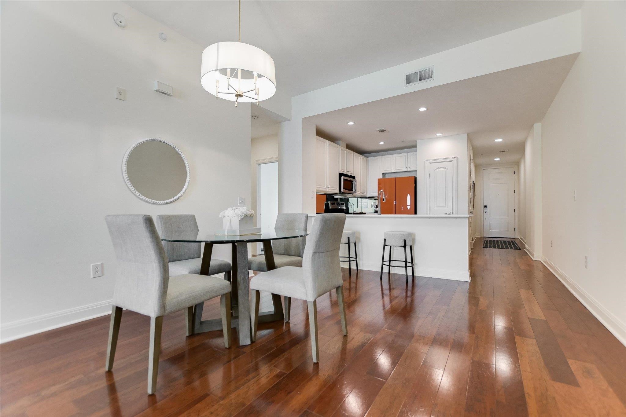 101 West Bank, Unit 52 Horseshoe Bay, TX 78657 - Photo 5 of 30 a dining room with wooden floor a chandelier a glass table and chairs