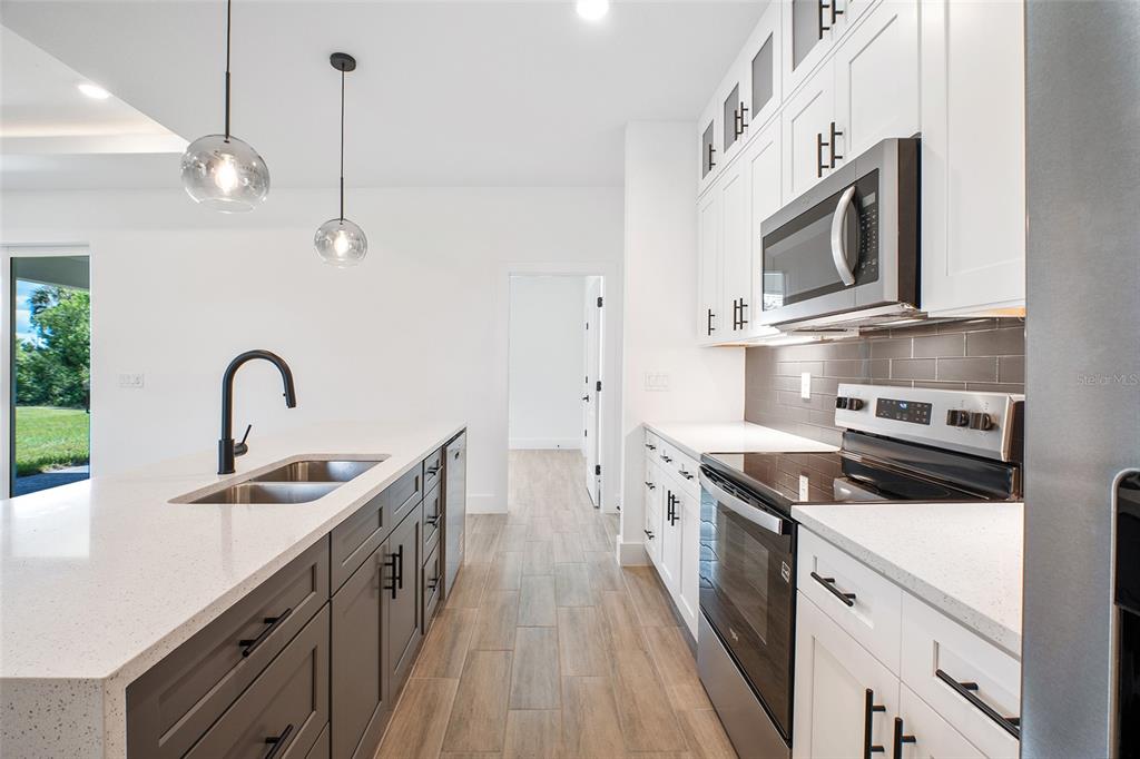 24419 Southwest Kingsway Circle Punta Gorda, FL 33983 - Photo 16 of 51 a kitchen with stainless steel appliances granite countertop a sink a stove and a refrigerator
