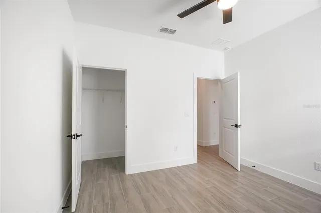 an empty room with wooden floor and a ceiling fan