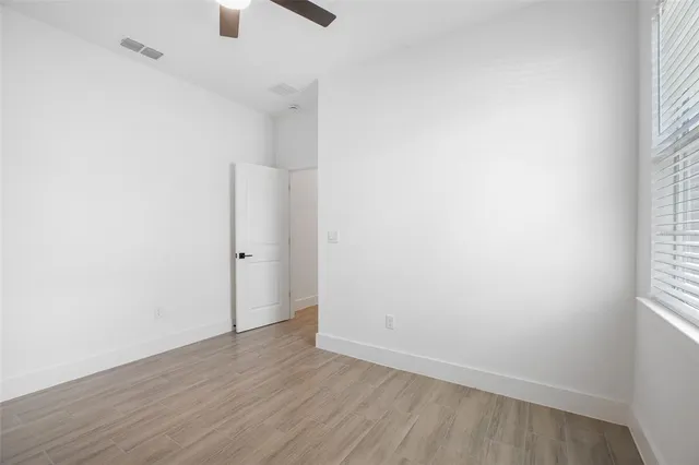 an empty room with wooden floor cabinet and windows