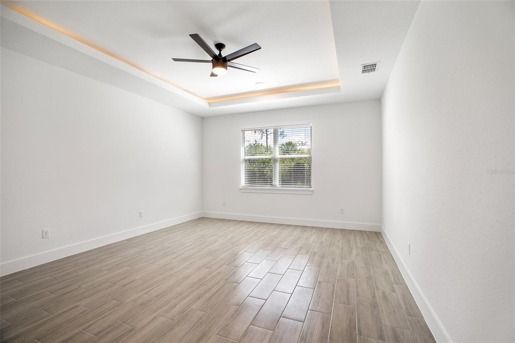 24419 Southwest Kingsway Circle Punta Gorda, FL 33983 - Photo 36 of 51 an empty room with wooden floor ceiling fan and windows