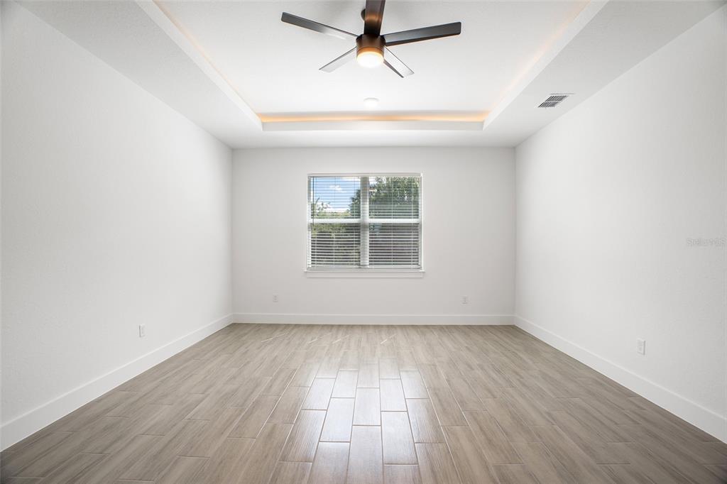 24419 Southwest Kingsway Circle Punta Gorda, FL 33983 - Photo 37 of 51 an empty room with wooden floor chandelier fan and windows