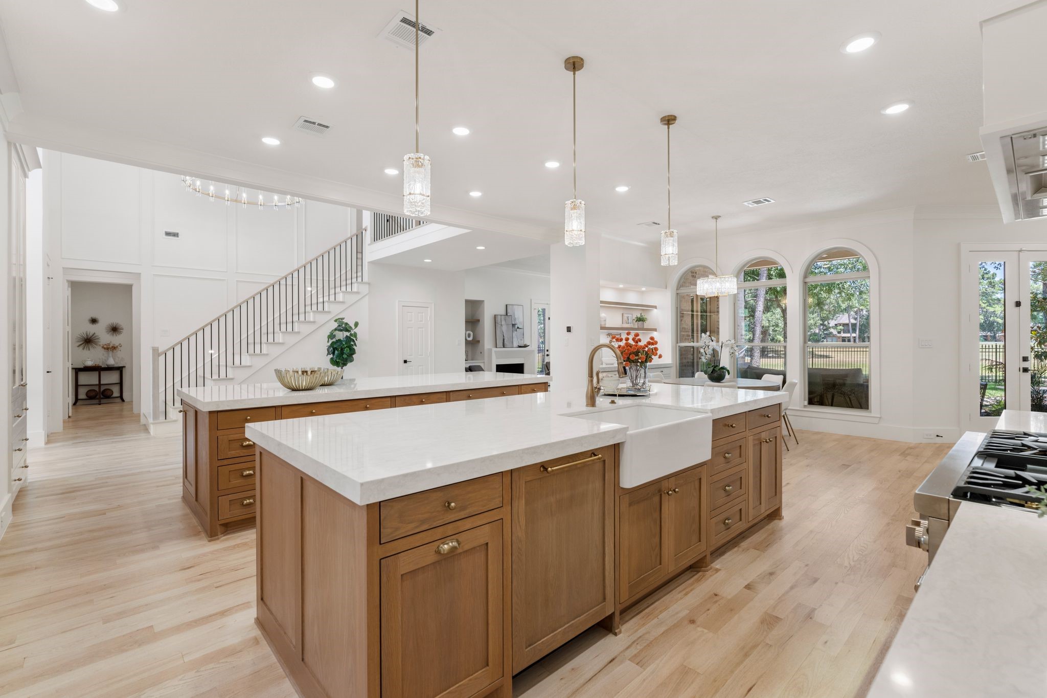 31 Hollymead Drive Spring, TX 77381 - Photo 14 of 50 This spacious kitchen features elegant wood custom cabinetry, a large central island with a farmhouse sink, a 2nd island with abudant storage and seating, and modern pendant lighting. The open layout seamlessly connects to a bright living area with large windows and French doors, offering plenty of natural light and views of the backyard.