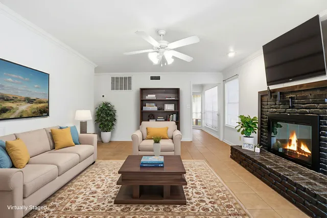 a view of an empty room with chandelier fan and fire place