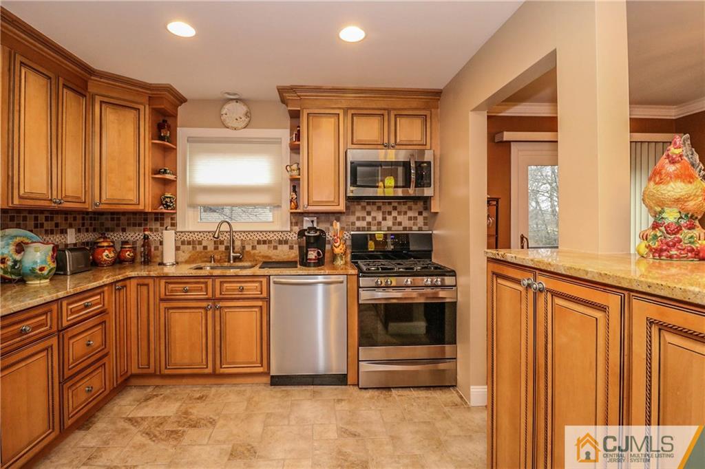 7307 Hana Road Edison, NJ 08817 - Photo 7 of 24 a kitchen with stainless steel appliances granite countertop a stove top oven