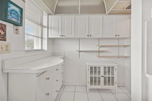 a kitchen with white cabinets and window