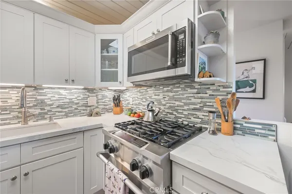 a kitchen with stainless steel appliances granite countertop a stove a sink and a microwave