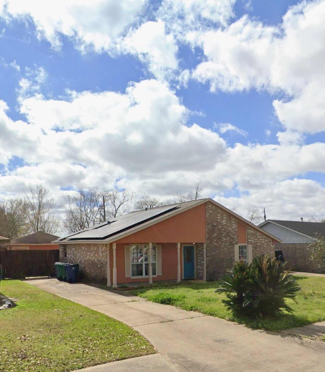 a view of a grey house with a big yard and potted plants