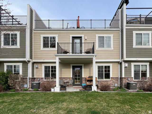1017 South 275 West Logan, UT 84321 - Photo 2 of 36 Rear view of house with a balcony, stone siding, and a lawn
