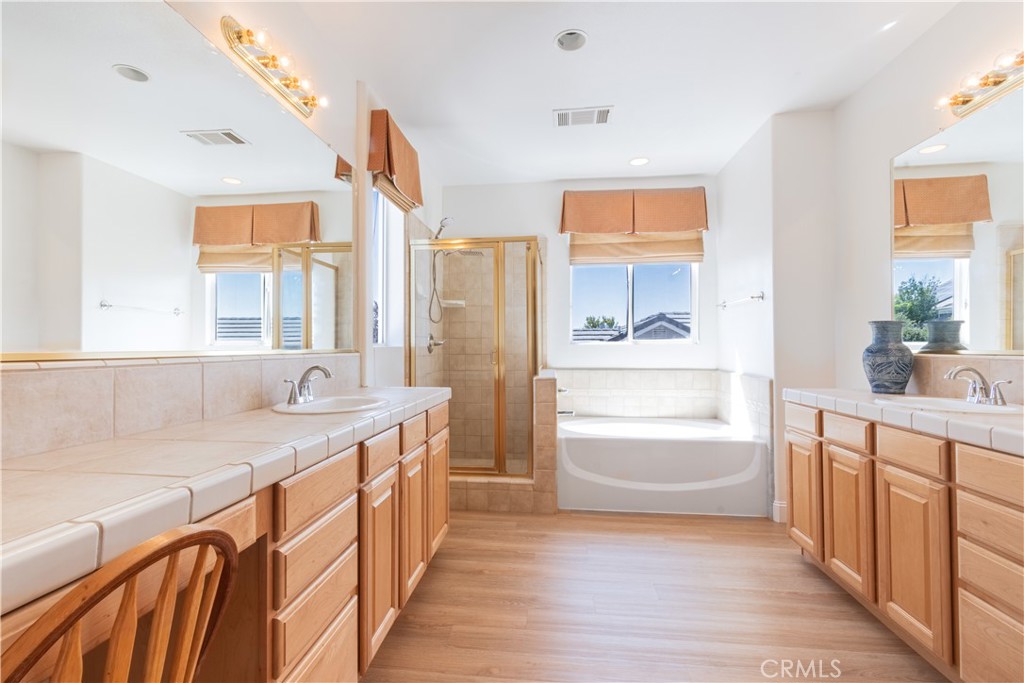 781 Angus Street Paso Robles, CA 93446 - Photo 19 of 34 Large primary bathroom with walk-in shower and separate tub. 2 large tiled vanities with his/her sinks, large mirrors and plenty of cabinets.