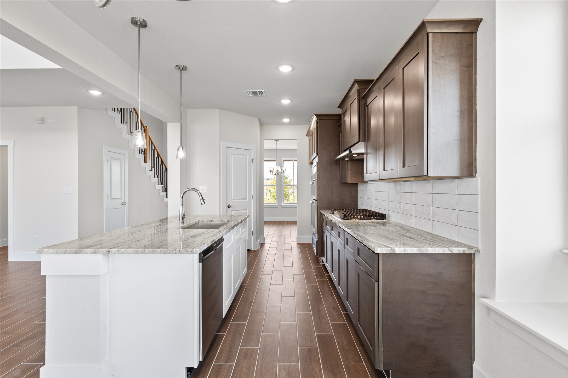 19705 Domino Champ Road Pflugerville, TX 78660 - Photo 19 of 38 Rich wood cabinetry contrasts beautifully with stone countertops in a thoughtfully designed modern kitchen.