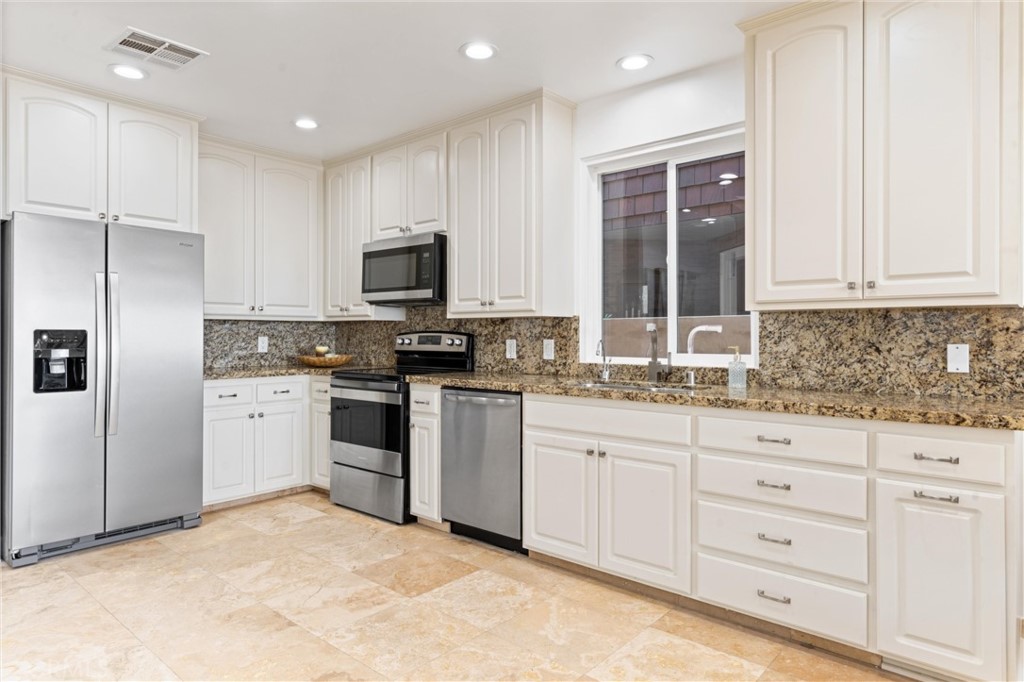 2804 West Oceanfront Newport Beach, CA 92663 - Photo 7 of 16 a kitchen with granite countertop white cabinets and stainless steel appliances