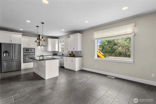 a kitchen with stainless steel appliances granite countertop a sink a stove a refrigerator and island