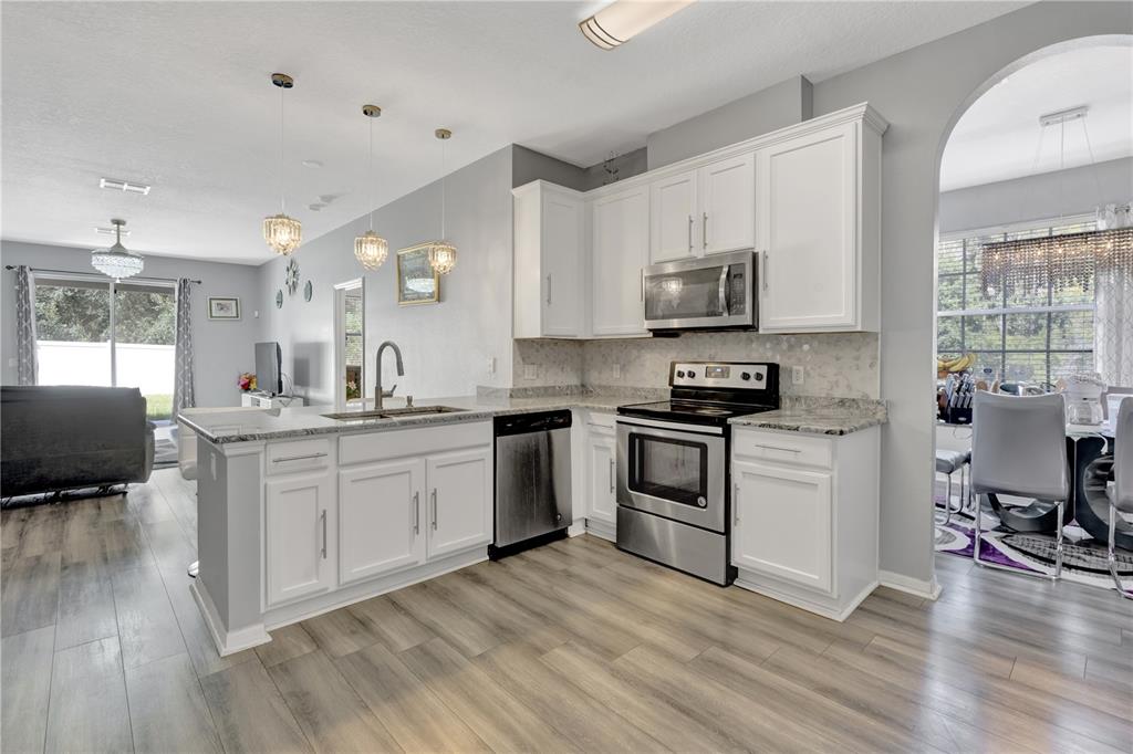 12847 Solola Way Trinity, FL 34655 - Photo 11 of 39 a kitchen with granite countertop a stove top oven sink and cabinets