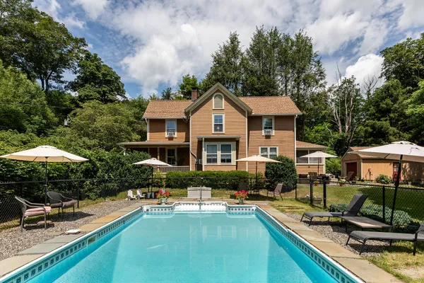 a front view of house and yard with swimming pool and furniture