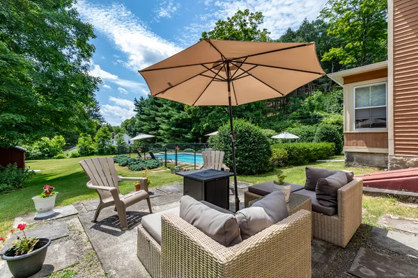 a view of a patio with couches table and chairs under an umbrella