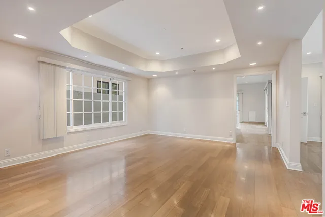 a view of an empty room with wooden floor and windows