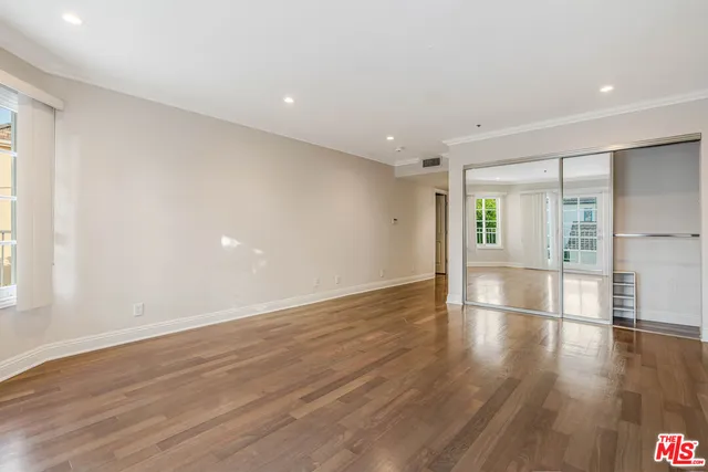 a view of empty room with wooden floor and fan