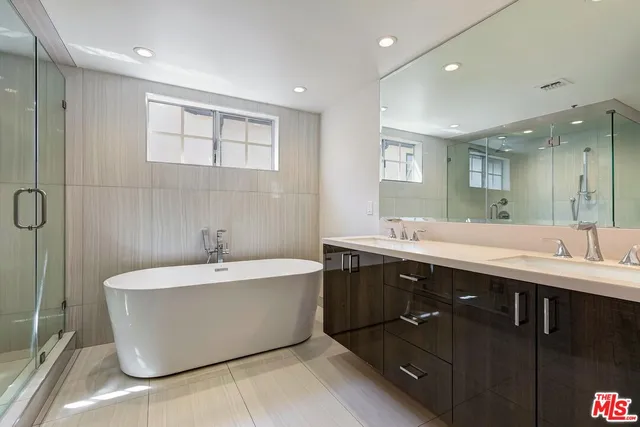 a spacious bathroom with a tub sink shower and mirror