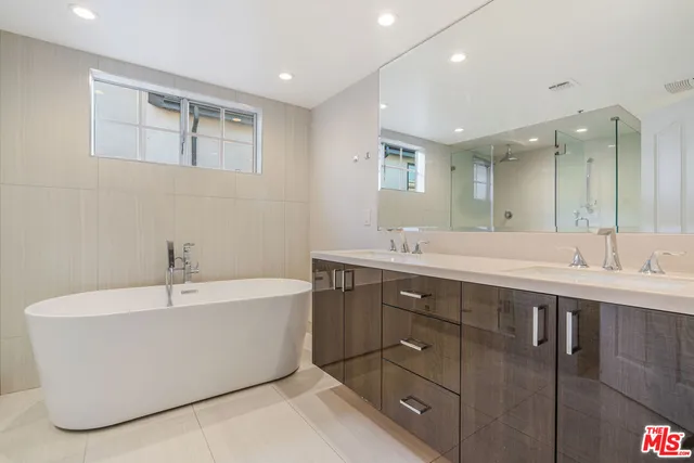 a spacious bathroom with a tub sink and mirror
