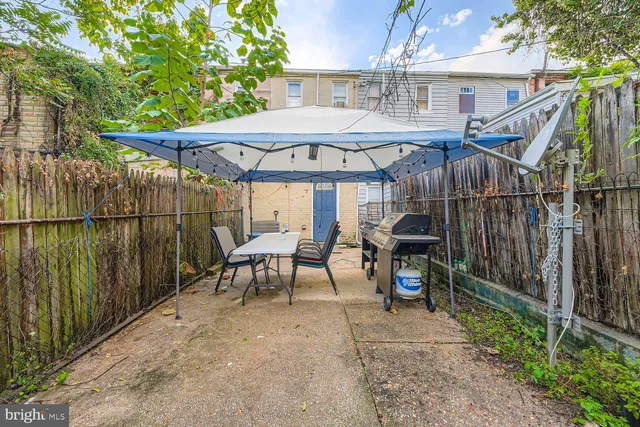 a view of a patio with table and chairs under an umbrella with a small yard