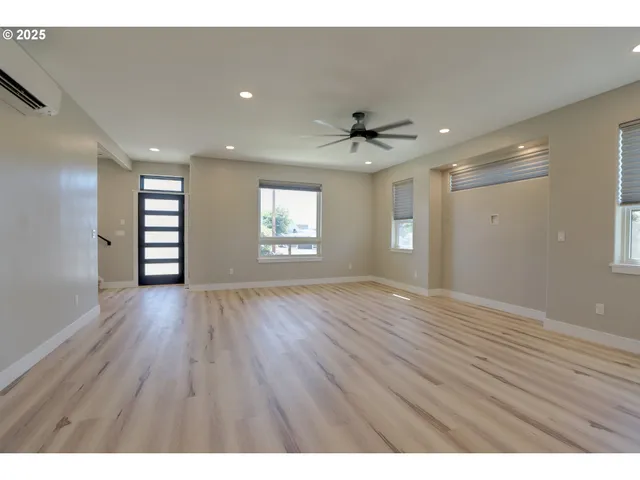 a view of an empty room with a window and wooden floor