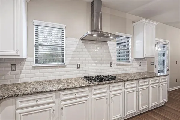 a kitchen with kitchen island granite countertop a sink cabinets and wooden floor