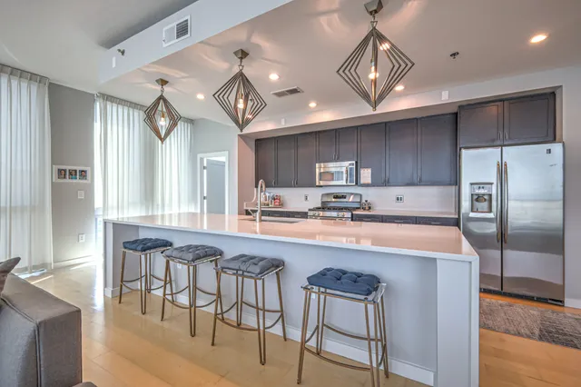 a large kitchen with stainless steel appliances granite countertop a table chairs sink and cabinets