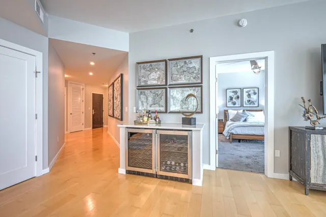 a spacious bedroom with a bed a window and potted plant on the dresser
