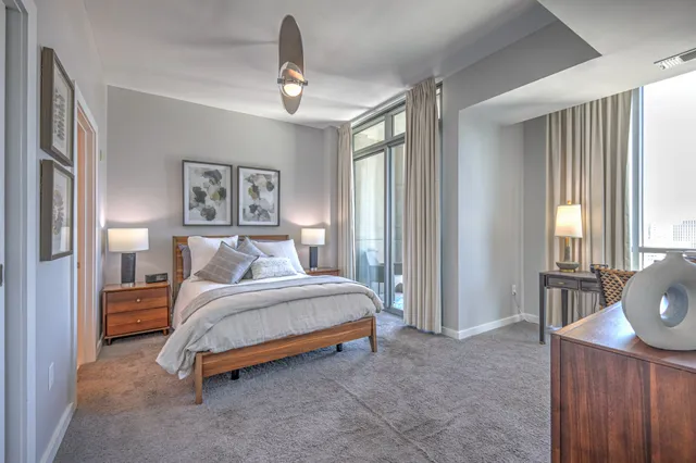 a bedroom with a balcony a bed and a dresser next to a window