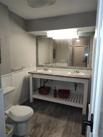 a bathroom with a granite countertop toilet sink and mirror