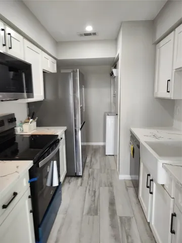 a kitchen with stainless steel appliances a sink dishwasher a refrigerator and a stove with wooden floor