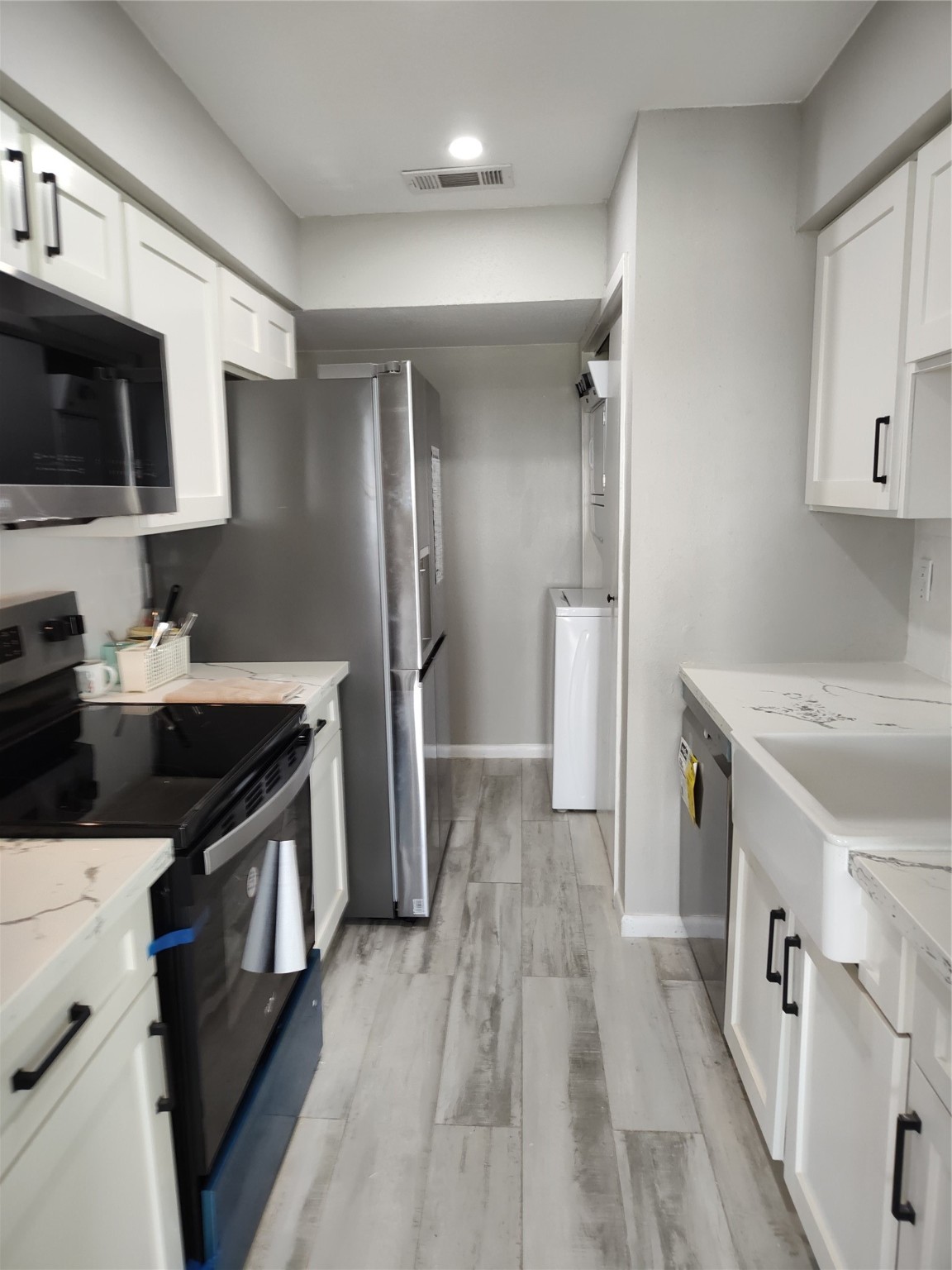 500 Tiki Drive, Unit 213 Tiki Island, TX 77554 - Photo 6 of 25 a kitchen with stainless steel appliances a sink dishwasher a refrigerator and a stove with wooden floor